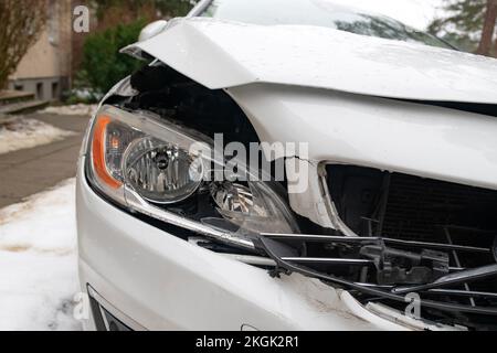 Nahaufnahme eines zertrümmerten Autos nach einem Unfall. Gebrochene Vorderseite des Fahrzeugs nach einem Autounfall in der Stadt. Stockfoto