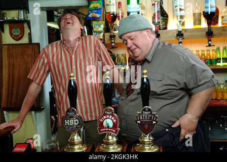 Auf dem Set „Doc Martin“ mit Martin Clunes (im Anzug), Ian McNeice (Hut) und John MacNeill (gestreiftes Hemd). Clunes wurde von Tomatensoße getäuscht Stockfoto