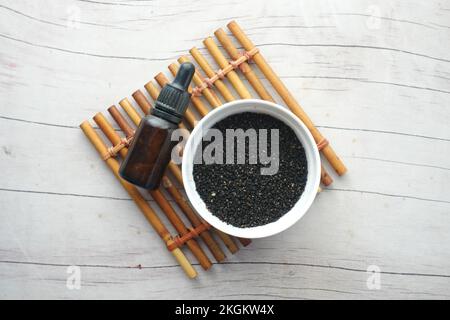 Schwarzer Sesam in einem Behälter mit Öl in einem Becher auf dem Tisch. Stockfoto