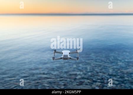 Eine Mikro-Drohne schwebt in der Luft über einem Gewässer Stockfoto