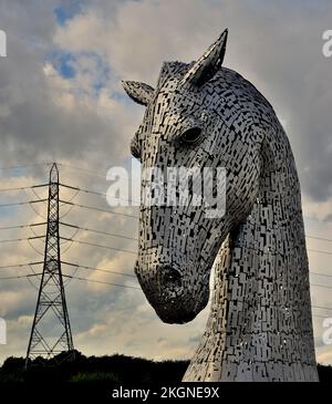 Duke, einer der Kelpies im Helix Country Park, Falkirk, Schottland, mit einem Strompylon im Hintergrund. Stockfoto