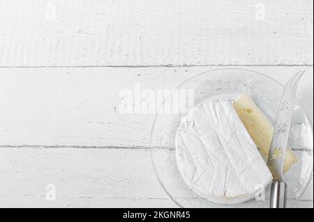 Weichkäse – französischer Brie, isoliert auf weißem Hintergrund mit Messer. Seitenansicht mit Kopierbereich. Flach verlegt Stockfoto