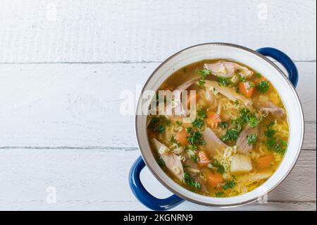 Topf mit hausgemachter Hühnchen-Nudelsuppe isoliert auf weißem Hintergrund von oben mit Kopierbereich. Mit alphabetischer Pasta zubereitet Stockfoto