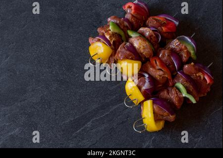 Rohe Schaschlik-Spieße, isoliert auf dunklem Hintergrund mit Kopierbereich Stockfoto