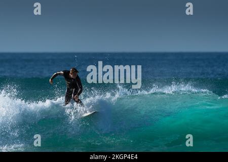 Spektakuläre Surfaktion als männlicher Surfer reitet auf einer Welle im Fistral in Newquay in Cornwall in England in Großbritannien. Stockfoto