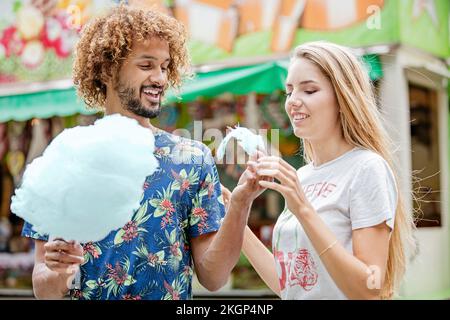 Ein junges Paar, das auf einem Jahrmarkt Süßseide isst Stockfoto