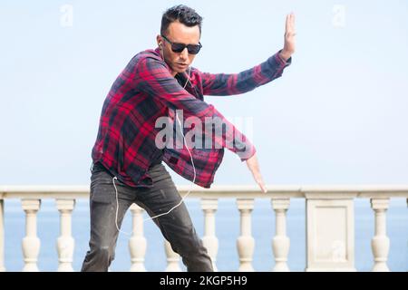 Ein Mann mit Sonnenbrille, der vor dem Geländer tanzt Stockfoto
