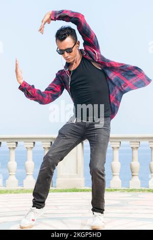 Ein Mann mit Sonnenbrille, der vor dem Geländer tanzt Stockfoto