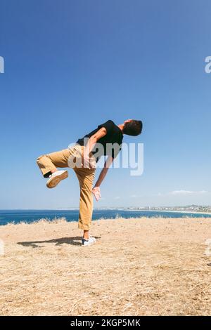 Ein Mann tanzt vor dem blauen Himmel am sonnigen Tag Stockfoto