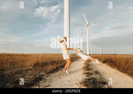Fröhliche Mutter, die sich vor Windturbinen dreht Stockfoto