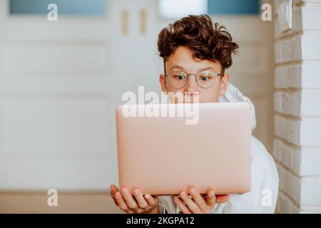 Schockierter Junge mit Notebook zu Hause Stockfoto