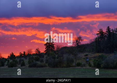Die aufgehende Sonne beleuchtet Wolken, die über der ländlichen Landschaft schweben Stockfoto