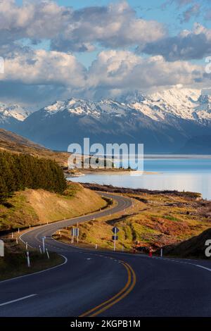 Neuseeland, Canterbury Region, gewundene Asphaltstraße mit Lake Pukaki und Mount Cook im Hintergrund Stockfoto