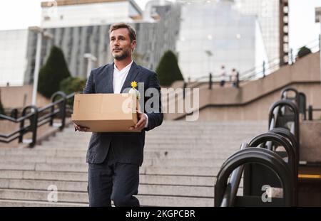 Besorgter Geschäftsmann mit Pappkarton, der die Treppe runterzieht Stockfoto