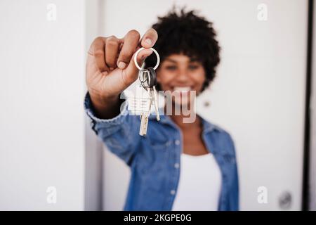 Glückliche Frau, die vor der Tür die Hausschlüssel zeigt Stockfoto