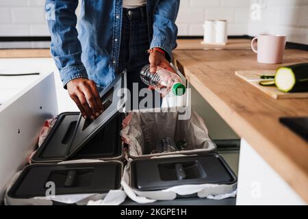 Eine Frau, die Plastikflaschen in der Küche zu Hause recycelt Stockfoto