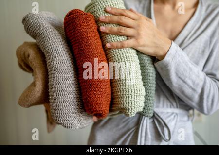 Eine Frau, die zu Hause saubere, gefaltete Pullover in der Hand hat Stockfoto