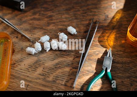 Pinzette und Zange mit Material auf dem Tisch in der Schmuckwerkstatt Stockfoto