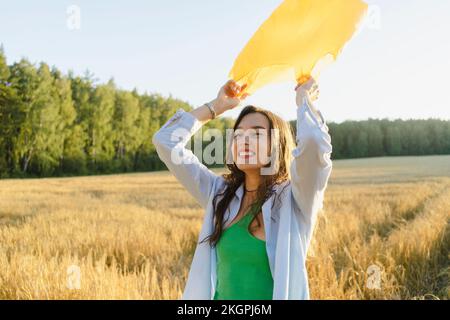 Glückliche Frau mit Müllsack, die auf dem Feld steht Stockfoto