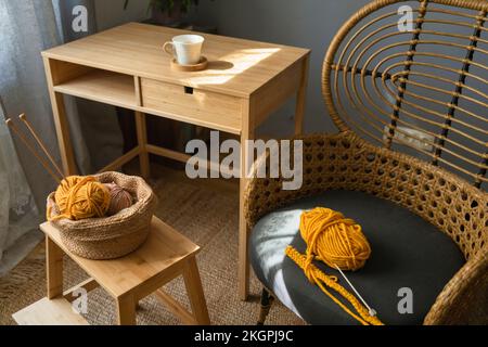 Wollknäuel im Korb und auf dem Stuhl zu Hause Stockfoto