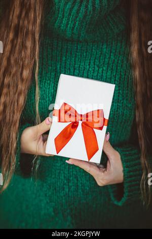 Eine Frau in grünem Pullover mit Weihnachtsgeschenk zu Hause Stockfoto