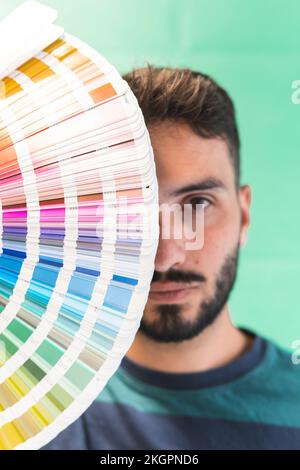 Junger Grafikdesigner mit Farbmuster vor dem Gesicht Stockfoto