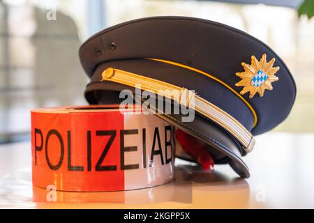 23. November 2022, Bayern, Manching: Eine bayerische Polizeimütze und ein Polizei-Cordon-Band liegen auf dem Tisch keltisch-römisches Museum. Einbrecher haben einen Goldschatz in Höhe von mehreren Millionen Euro aus der keltischen Zeit in Manching, Oberbayern, erobert. Wie ein Sprecher der Bayerischen Staatlichen Kriminalpolizei (LKA) am Dienstag berichtete, hatten die Täter das Museum in Manching in der vergangenen Nacht betreten und den Schatz, der 1999 in der Nähe von Manching entdeckt wurde, vollständig gestohlen. Foto: Peter Kneffel/dpa Stockfoto