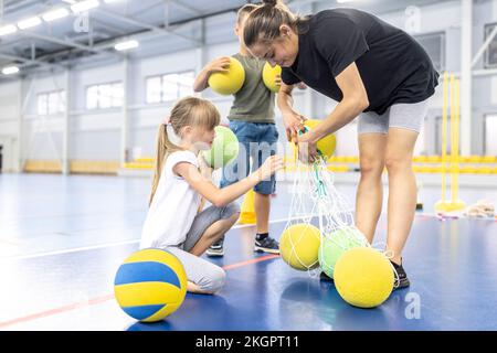 Lehrer und Schüler entfernen Bälle aus dem Netz am Schulsportplatz Stockfoto