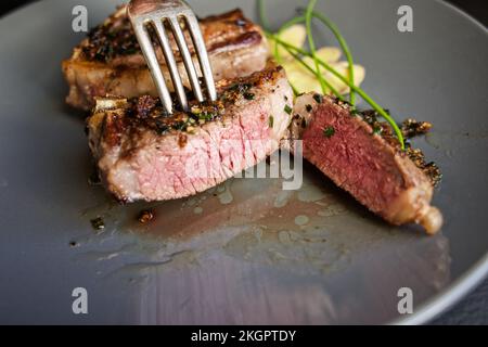 Gekochte Lammkoteletts, auf einem Teller mit klassischer Kräuter- und Ingwergarnierung ausgestellt. Stockfoto