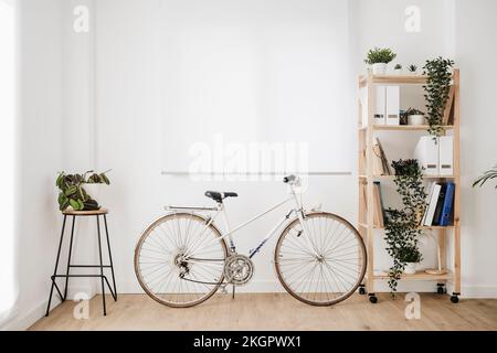 Fahrrad auf Regal vor weißer Wand im modernen Büro Stockfoto