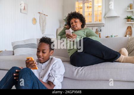 Mutter und Sohn, die zu Hause Smartphones benutzen Stockfoto