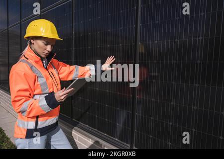 Junge Ingenieurin, die einen Tablet-PC bei Solarmodulen verwendet Stockfoto