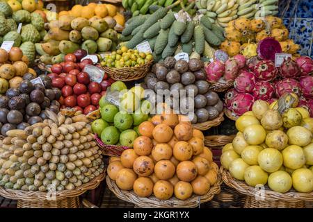 Farbenfrohe Haufen exotischer Früchte werden auf dem überdachten Markt verkauft und im hellen Herbstlicht in Funchal, Madeira, Portugal, gedreht Stockfoto