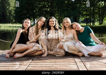 Lächelnde junge Freunde, die auf dem Pier sitzen Stockfoto