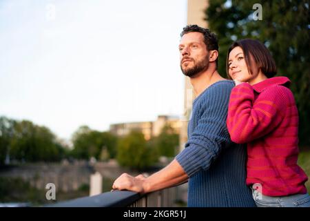 Romantisches Paar in warmer Kleidung, das neben dem Geländer steht Stockfoto