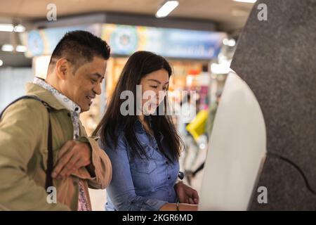 Lächelnder Mann mit reifer Frau am Geldautomaten Stockfoto