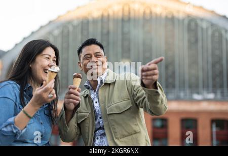 Glückliches, reifes Paar, das vor dem Gebäude Eiscreme hält Stockfoto