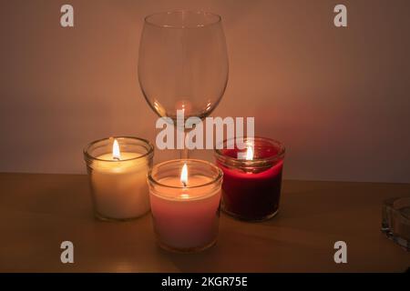 Foto eines leeren Weinglases und brennender Kerzen Stockfoto