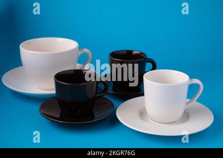 Foto von leeren Kaffeetassen mit Untertassen auf blauem Hintergrund Stockfoto