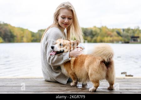 Lächelnde Frau mit Pembroke welsh Corgi auf dem Steg Stockfoto