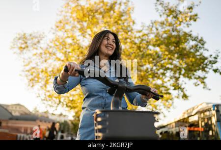 Glückliche Frau mit Elektrofahrrad auf dem Fußweg Stockfoto