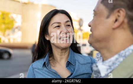 Lächelnde, reife Frau, die einen Mann auf dem Fußweg ansieht Stockfoto