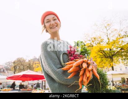 Glückliche Frau, die Bio-Gemüse auf dem Markt hält Stockfoto