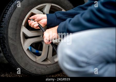 Die Hand des Mannes füllt Luft in den Reifen an der Tankstelle Stockfoto