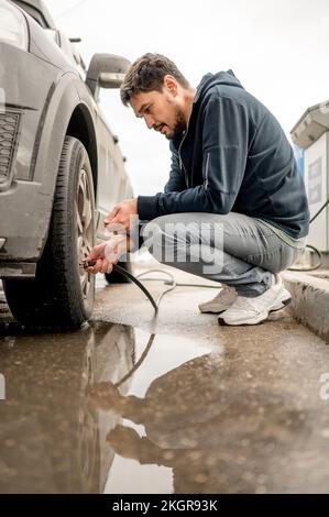 Mann, der an der Tankstelle Luft in den Reifen füllt Stockfoto