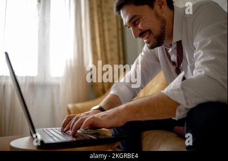 Glücklicher Geschäftsmann, der von zu Hause aus an einem Notebook arbeitet Stockfoto