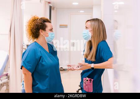 Krankenschwestern tragen Masken, die im Krankenhaus miteinander reden Stockfoto