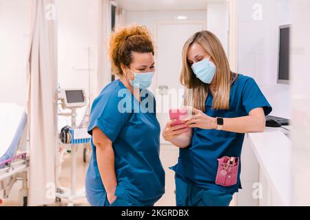 Krankenschwester mit Kollege am Smartphone im Krankenhaus Stockfoto