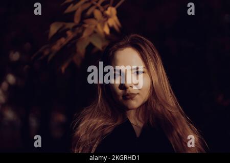 Lächelnde junge Frau mit langen Haaren im Park Stockfoto