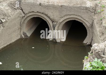 Abwasserrohr. Kanal mit schmutzigem Wasser. Ablassen von Abfällen. Infrastrukturdetails. Stockfoto